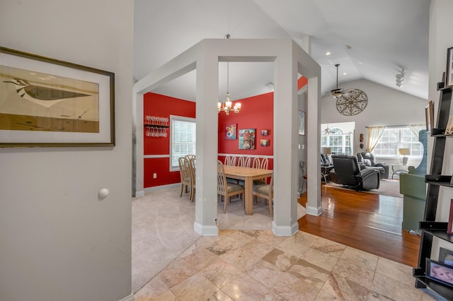 carpeted dining room with ceiling fan with notable chandelier and high vaulted ceiling