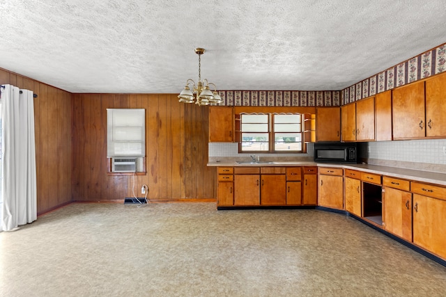 kitchen with a textured ceiling, an inviting chandelier, decorative light fixtures, cooling unit, and sink