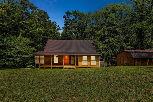 rear view of house featuring a lawn and a storage unit