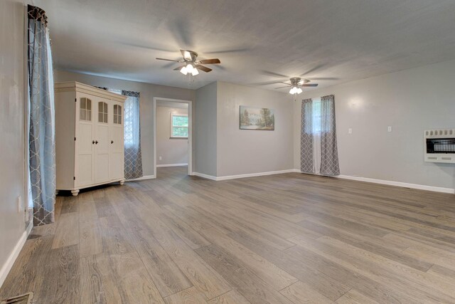 unfurnished room with ceiling fan, light wood-type flooring, and heating unit