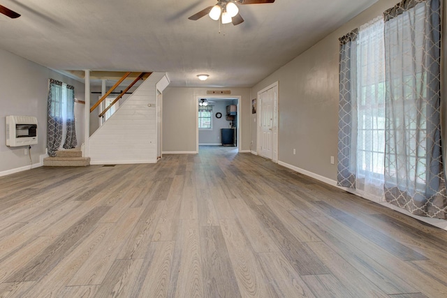 unfurnished living room featuring wood-type flooring, heating unit, and ceiling fan