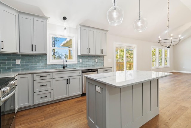 kitchen with gray cabinets, sink, decorative light fixtures, and light wood-type flooring