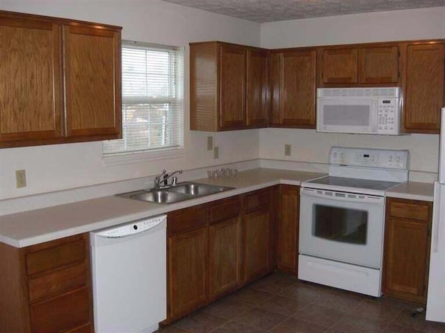 kitchen featuring sink, dark tile patterned floors, and white appliances