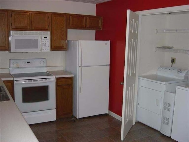 kitchen featuring washer / clothes dryer, dark tile patterned flooring, and white appliances