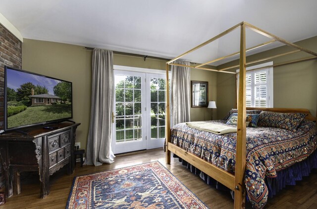 bedroom featuring access to exterior, brick wall, and hardwood / wood-style floors