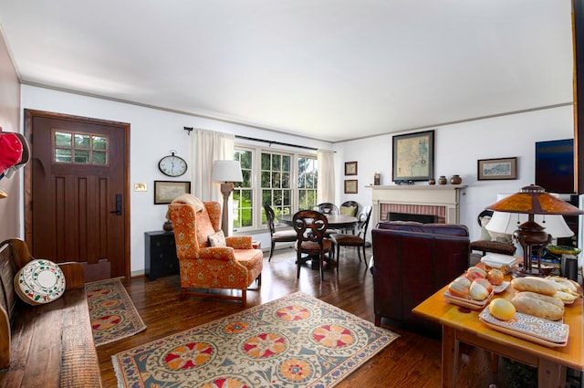 living room with a brick fireplace, dark hardwood / wood-style flooring, and ornamental molding