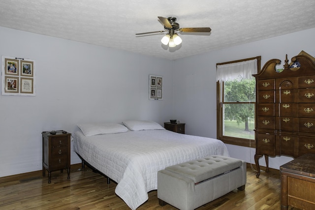 bedroom featuring a textured ceiling, ceiling fan, and dark wood-type flooring