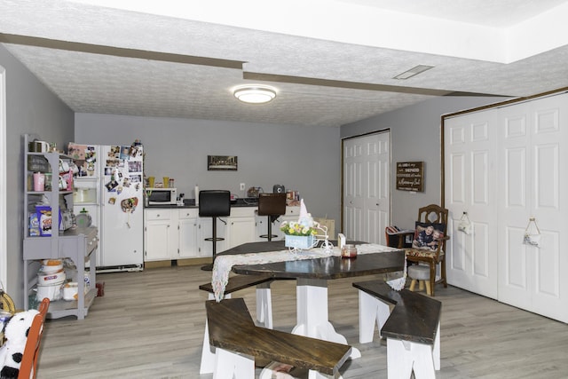 dining space with a textured ceiling and light hardwood / wood-style flooring