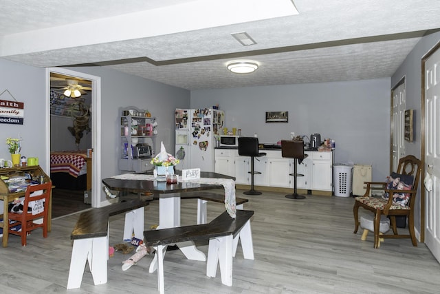 dining space with light hardwood / wood-style floors and a textured ceiling