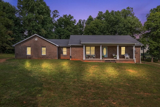 ranch-style home featuring covered porch and a yard