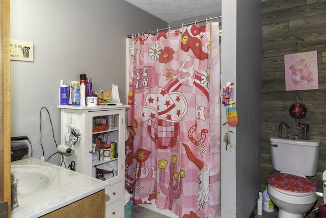 bathroom with vanity, a textured ceiling, toilet, and wood walls