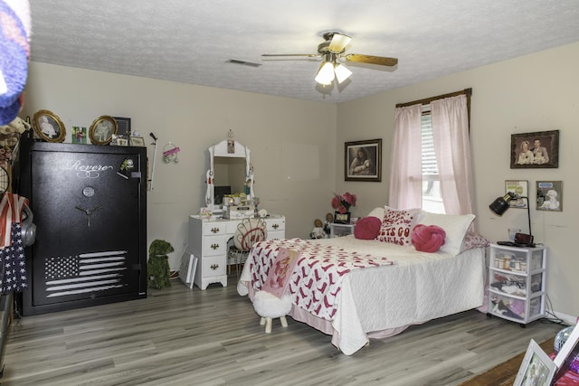 bedroom featuring hardwood / wood-style floors, ceiling fan, and a textured ceiling