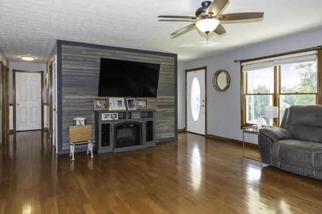 living room with ceiling fan, a fireplace, dark hardwood / wood-style flooring, and a textured ceiling