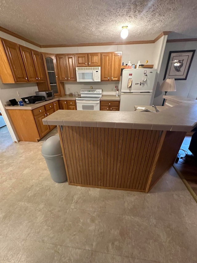 kitchen with a textured ceiling, white appliances, light tile patterned floors, and kitchen peninsula