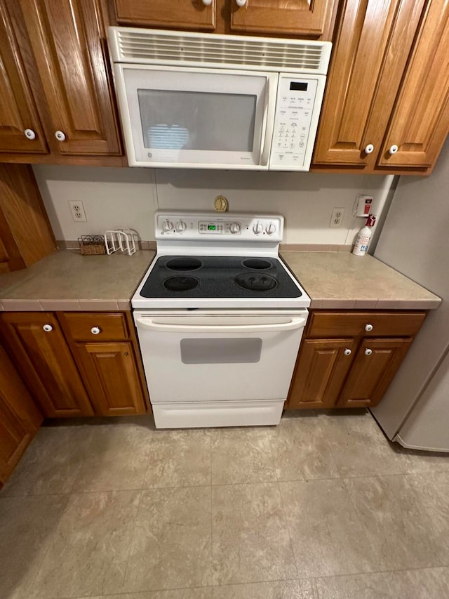 kitchen featuring light tile patterned flooring and white appliances