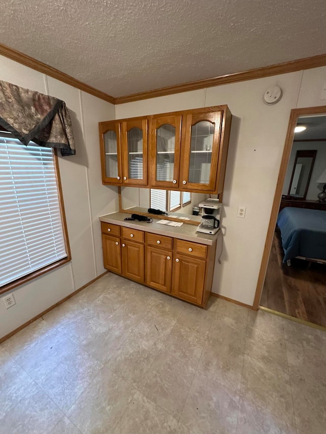 kitchen featuring a textured ceiling, light wood-type flooring, and ornamental molding