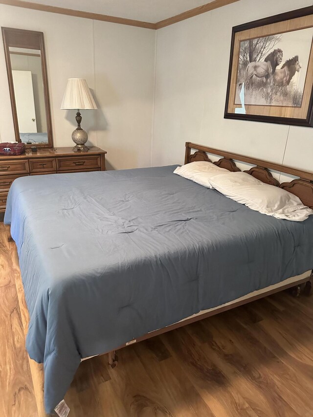 bedroom featuring wood-type flooring and crown molding