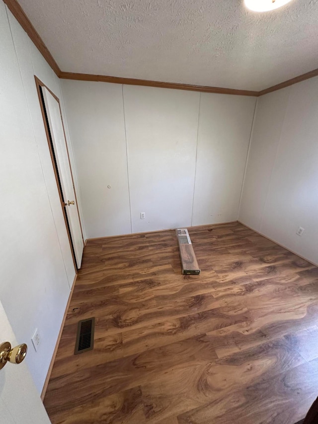 unfurnished bedroom featuring crown molding, a textured ceiling, and hardwood / wood-style flooring