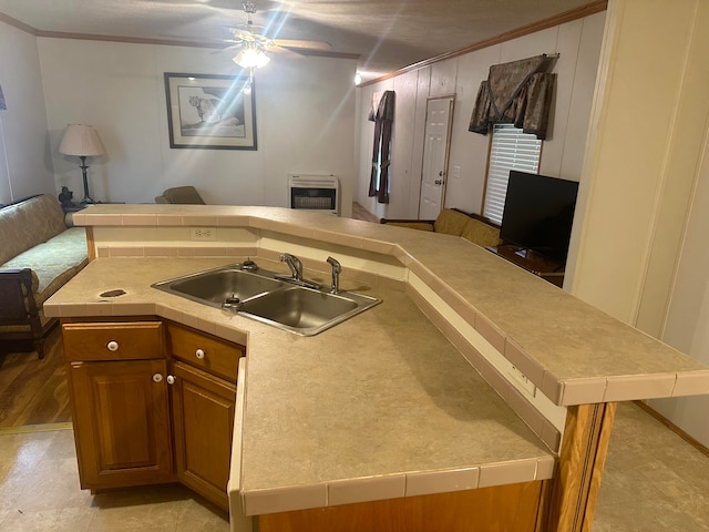 kitchen with light tile patterned floors, crown molding, sink, and ceiling fan