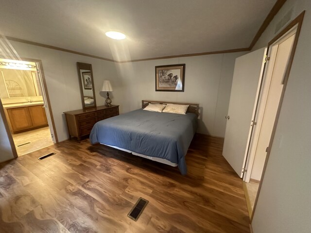 bedroom with ensuite bathroom, ornamental molding, and hardwood / wood-style floors