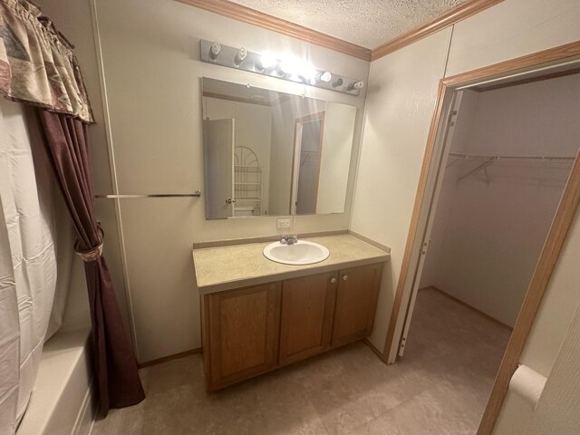 bathroom with vanity, ornamental molding, shower / tub combo, a textured ceiling, and tile patterned flooring