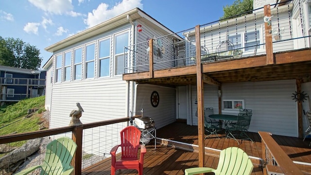 rear view of property featuring a balcony and a wooden deck