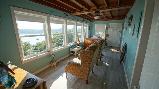 sitting room featuring beam ceiling, wood-type flooring, a wealth of natural light, and wooden ceiling