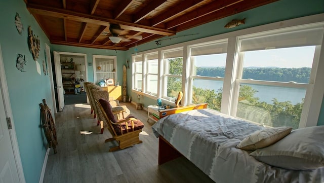 bedroom with a water view, wooden ceiling, hardwood / wood-style floors, and beam ceiling