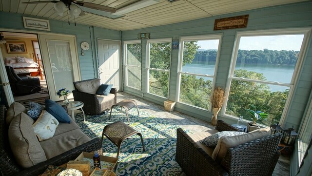 sunroom / solarium featuring a water view and ceiling fan