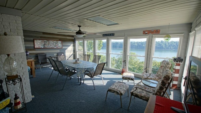 sunroom with a water view and ceiling fan