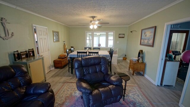 living room with light hardwood / wood-style floors, ornamental molding, a textured ceiling, and ceiling fan