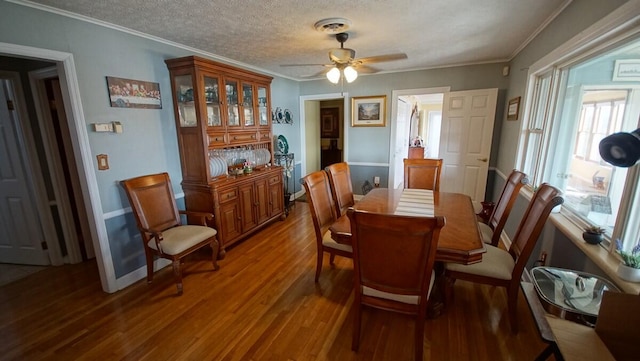 dining area with a textured ceiling, hardwood / wood-style flooring, crown molding, and ceiling fan