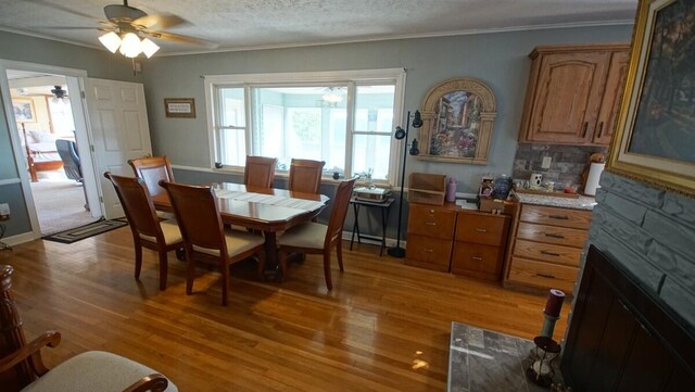 dining space featuring ornamental molding, a textured ceiling, ceiling fan, and light hardwood / wood-style floors