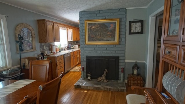 living room featuring a fireplace, ornamental molding, sink, light hardwood / wood-style floors, and a textured ceiling