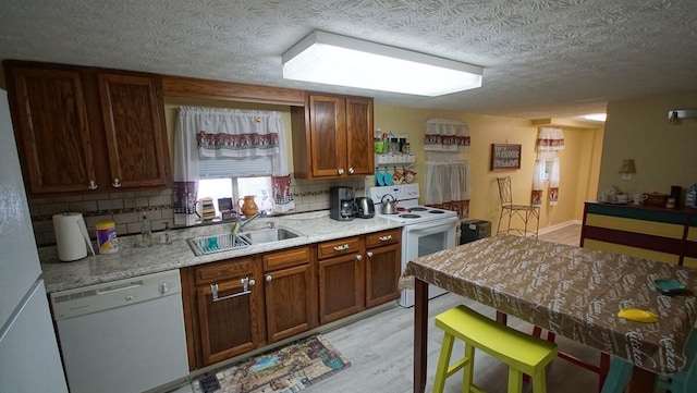 kitchen featuring sink, light hardwood / wood-style flooring, decorative backsplash, and white appliances