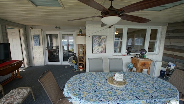 dining room featuring carpet, brick wall, and ceiling fan