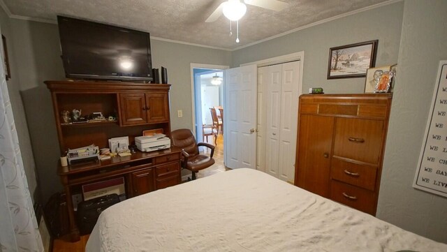 bedroom featuring ornamental molding, a closet, a textured ceiling, and ceiling fan