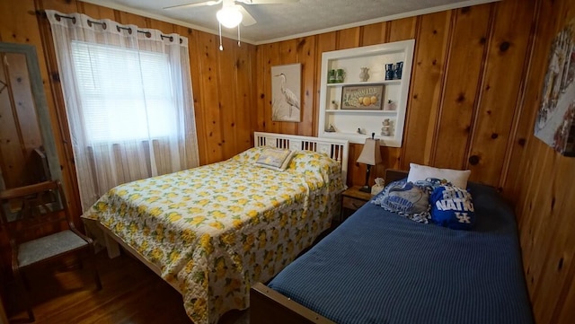 bedroom with wood walls, wood-type flooring, ceiling fan, and crown molding