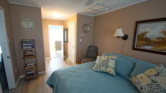 bedroom featuring a textured ceiling, ceiling fan, wood-type flooring, and ornamental molding