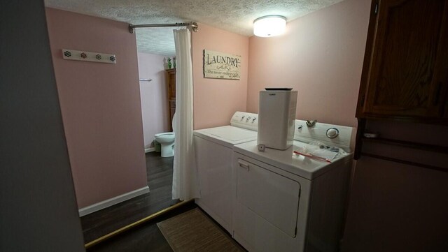 washroom with washer and dryer, a textured ceiling, and dark hardwood / wood-style floors