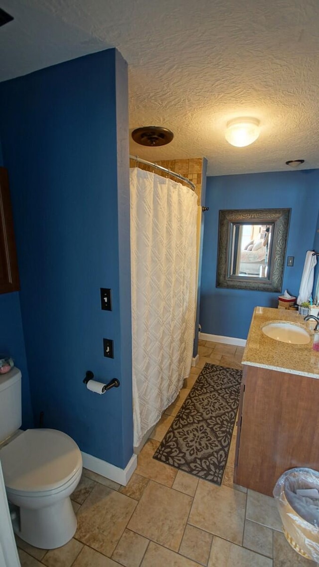 bathroom with vanity, toilet, a textured ceiling, and tile patterned flooring