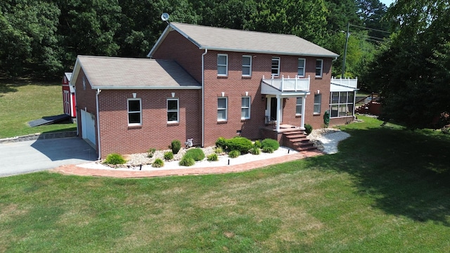 colonial house with a balcony, a garage, and a front lawn