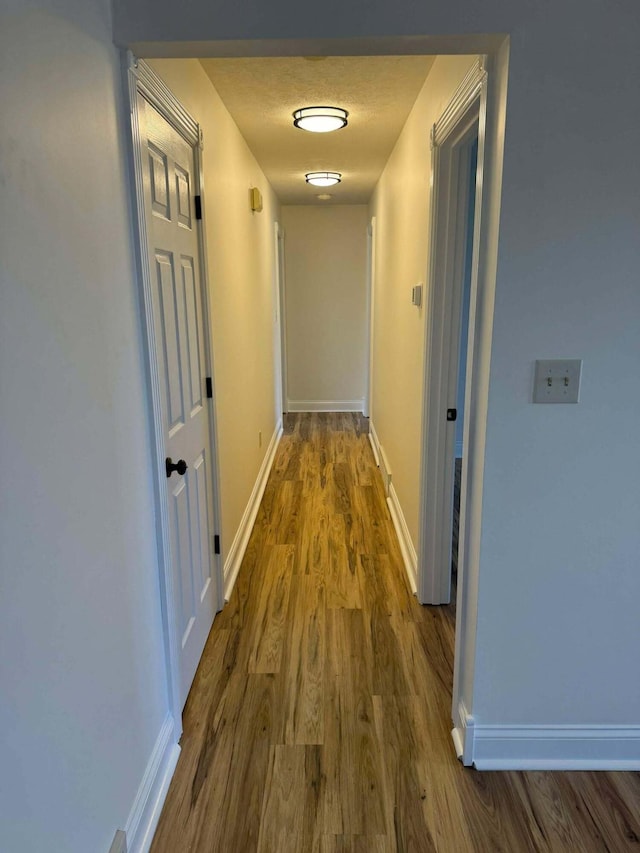 corridor featuring hardwood / wood-style flooring and a textured ceiling