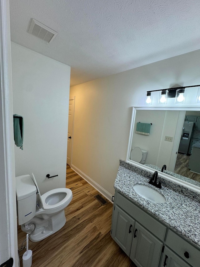 bathroom with vanity, hardwood / wood-style floors, a textured ceiling, and toilet