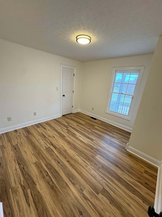 spare room featuring hardwood / wood-style flooring and a textured ceiling