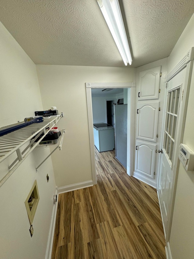 clothes washing area featuring hardwood / wood-style flooring and a textured ceiling