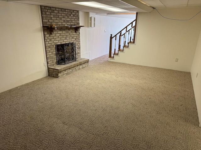 basement with a drop ceiling, a brick fireplace, and carpet