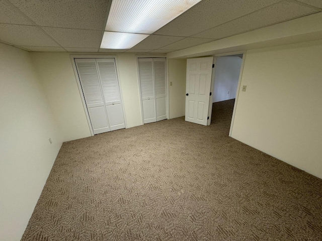 basement with a paneled ceiling and carpet