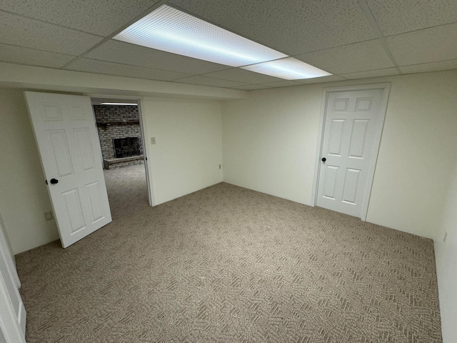 basement with a brick fireplace, a paneled ceiling, and carpet flooring