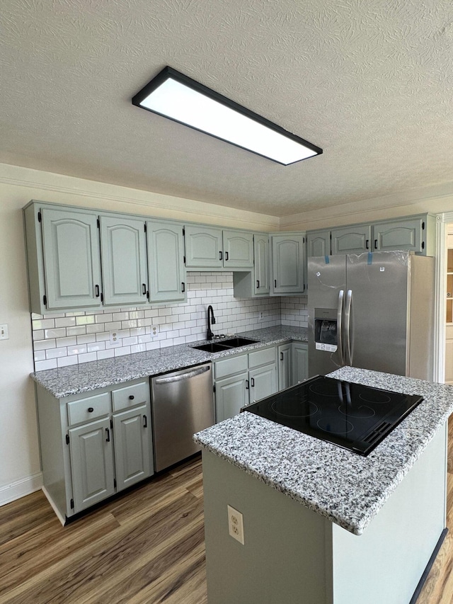 kitchen with sink, appliances with stainless steel finishes, backsplash, a textured ceiling, and dark hardwood / wood-style flooring